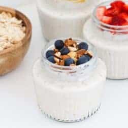 Glass jars filled with overnight oats and topped with fruits and nuts.