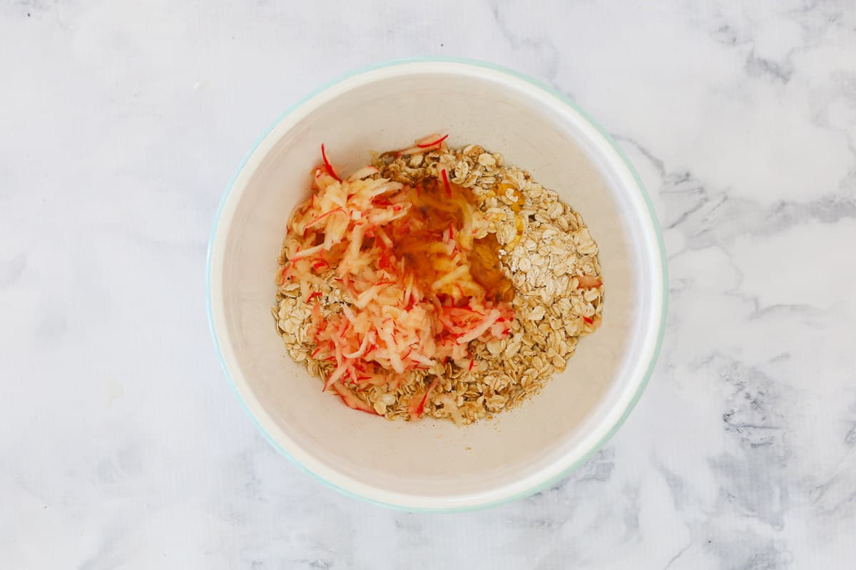 Grated red apple and oats in a bowl.