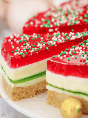 A Christmas themed jelly cake with a slice being removed.