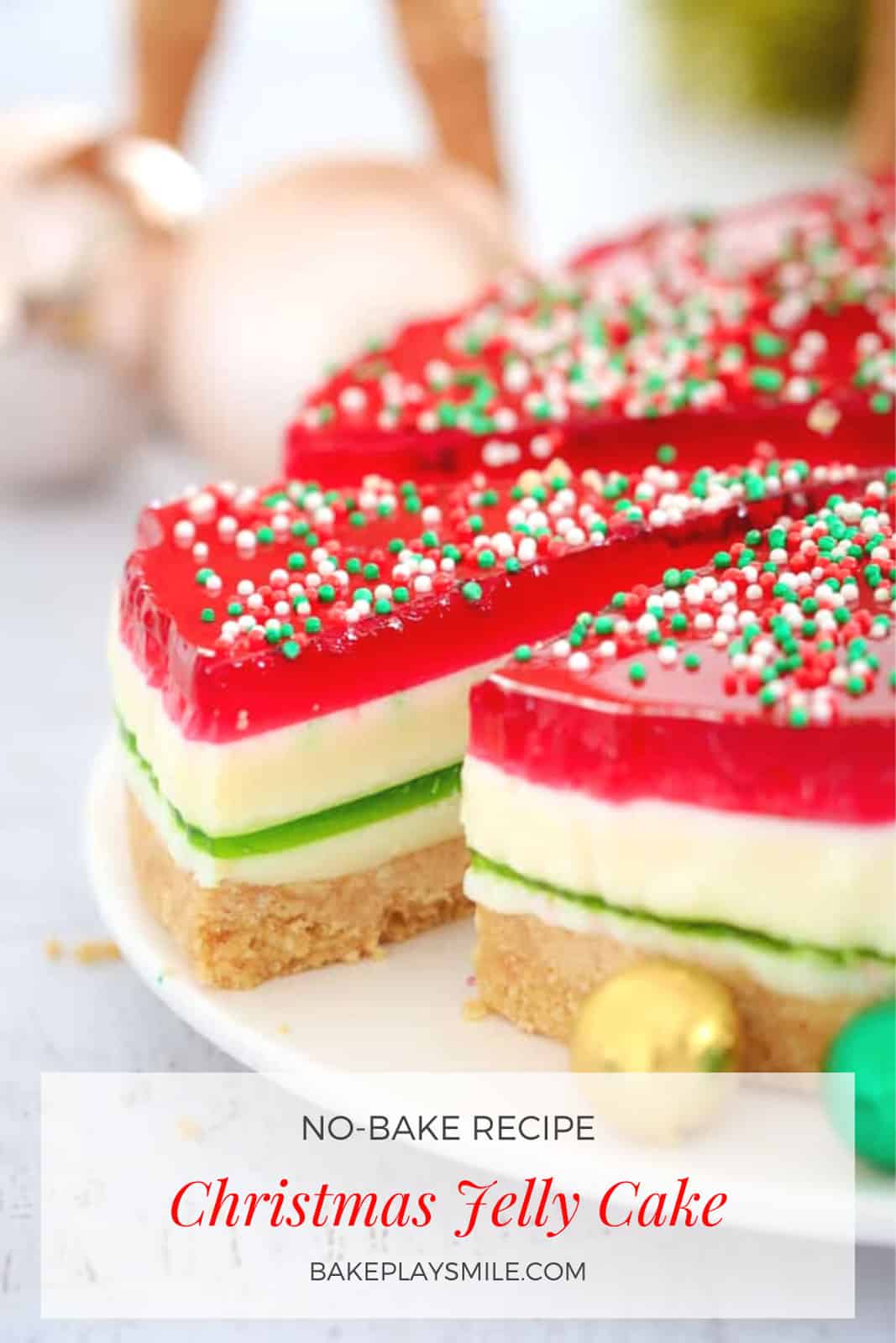 A colourful Pinterest image of a  jelly cake with a Christmas theme of white, red and green layers, decorated with sprinkles and chocolate decorations.