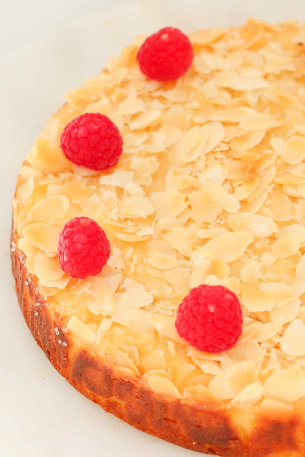 Overhead shot of a lemon cake topped with raspberries and flaked almonds