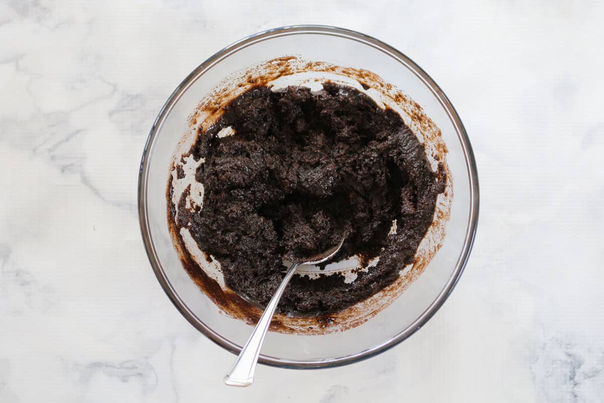 Oreos crushed and mixed with butter in a glass bowl
