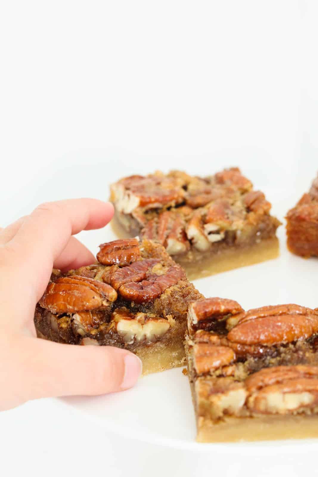 A hand grabbing a pecan pie bar