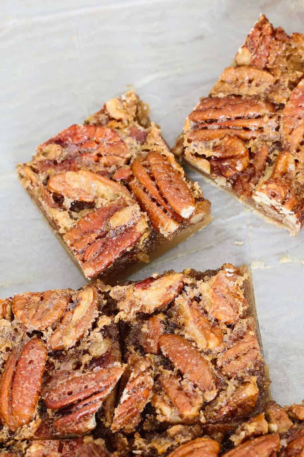 An overhead shot of pecan pie bars with a crunchy layer of pecan halves on top