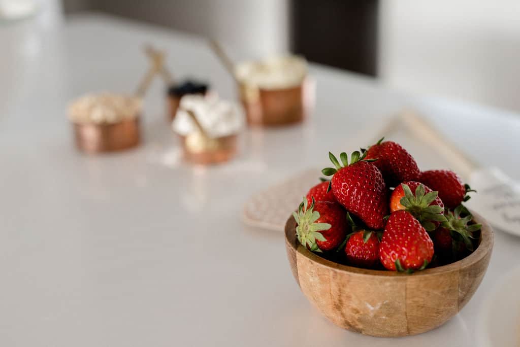 A bowl of strawberries on a white bench.