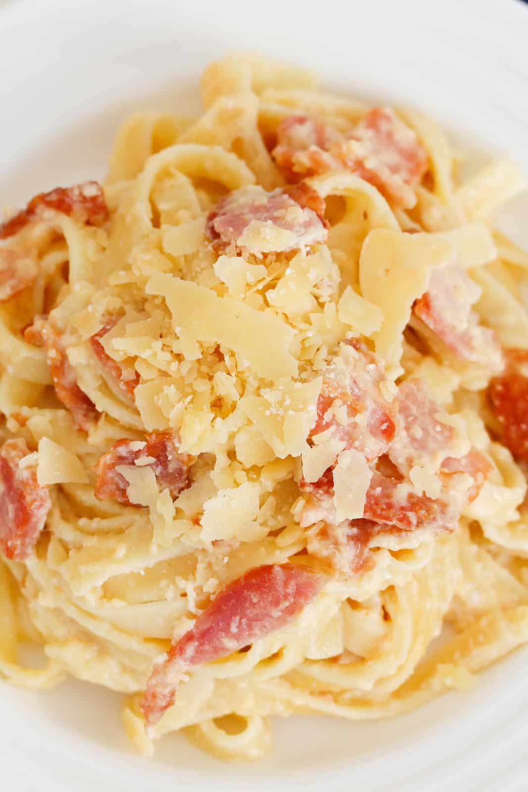 Closeup shot of fettuccine carbonara with bacon and parmesan flakes.
