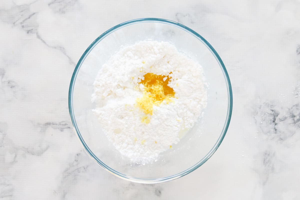 Top view of flour, lemon zest, and coconut in glass bowl
