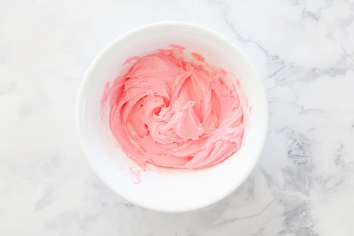 Pink buttercream frosting in white bowl.