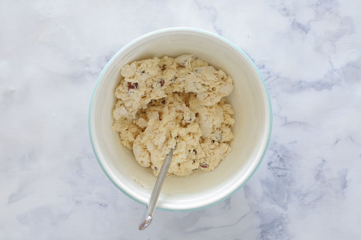Fruit scones dough in white mixing bowl with spoon
