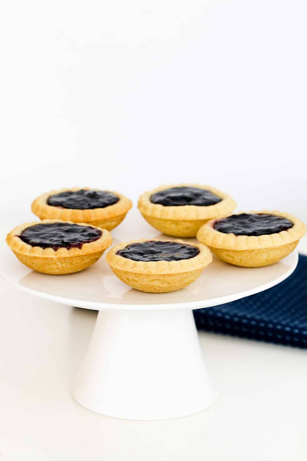 A cake stand topped with five mini jam tarts.