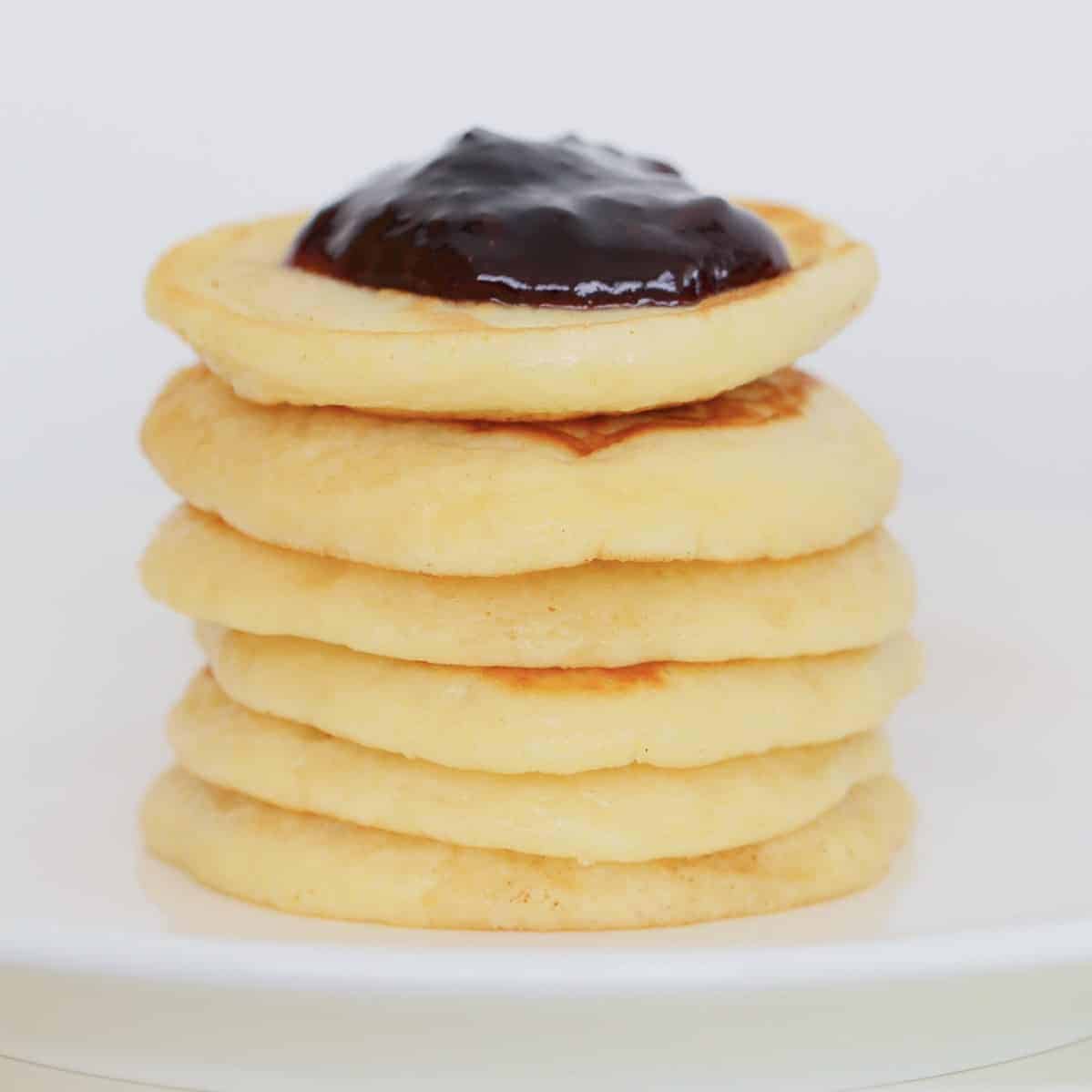 A stack of pikelets on a white plate.