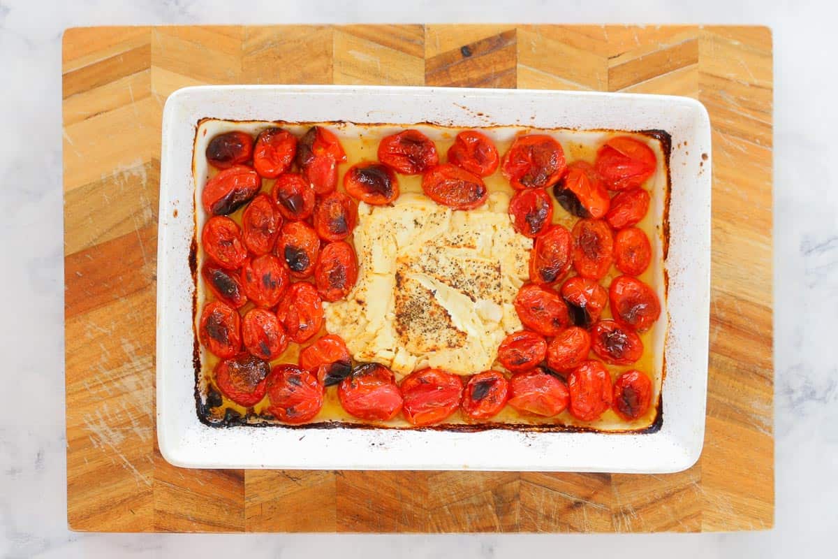 Soft baked feta and charred tomatoes in a baking dish.