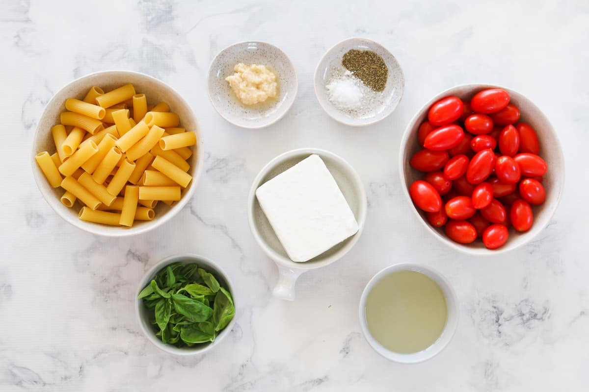 The ingredients for baked feta pasta in individual bowls.