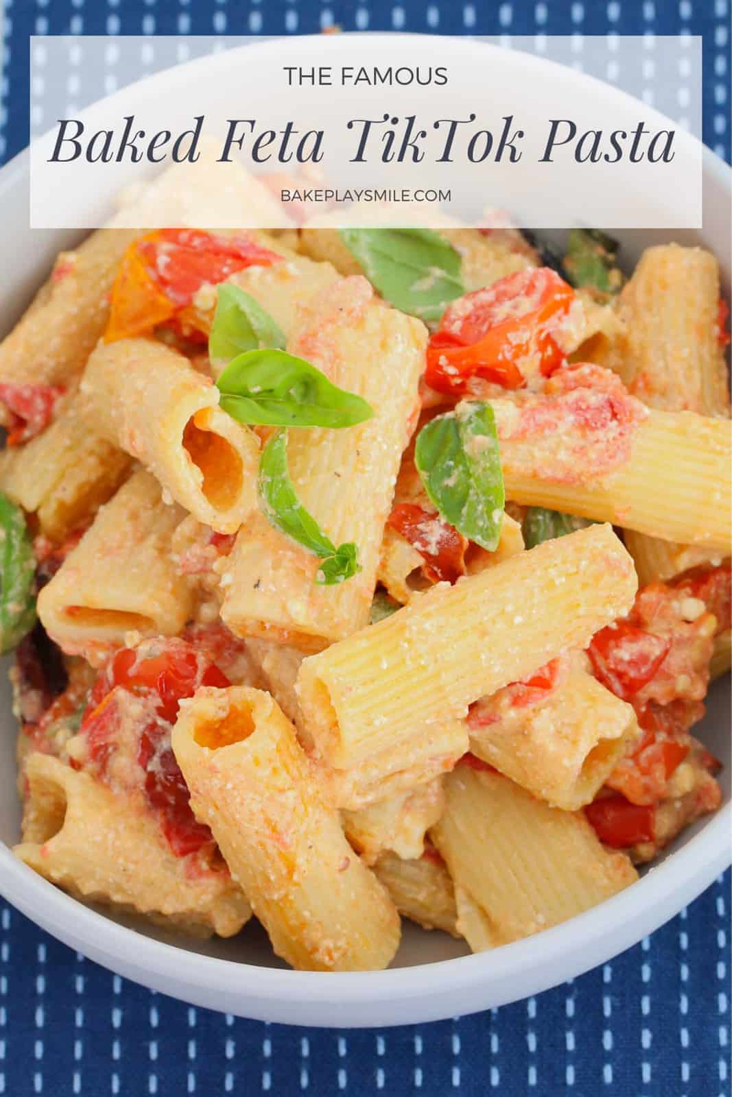 A bowl of pasta mixed with a creamy feta and tomato sauce, and basil leaves sprinkled over the top.