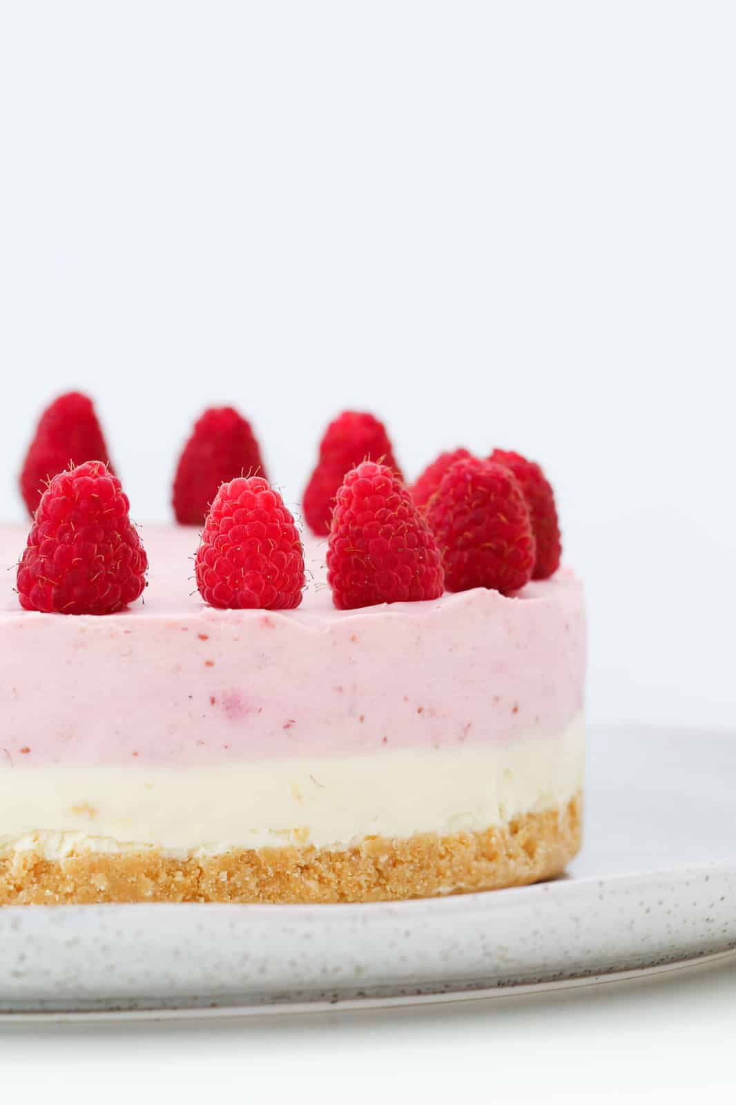 close up shot of cheesecake with white and pink layers garnished with fresh berries