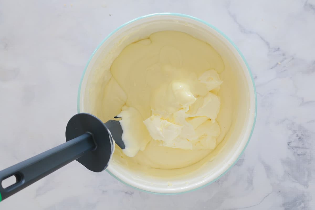 close up of white chocolate cheesecake mix being blended in mixing bowl