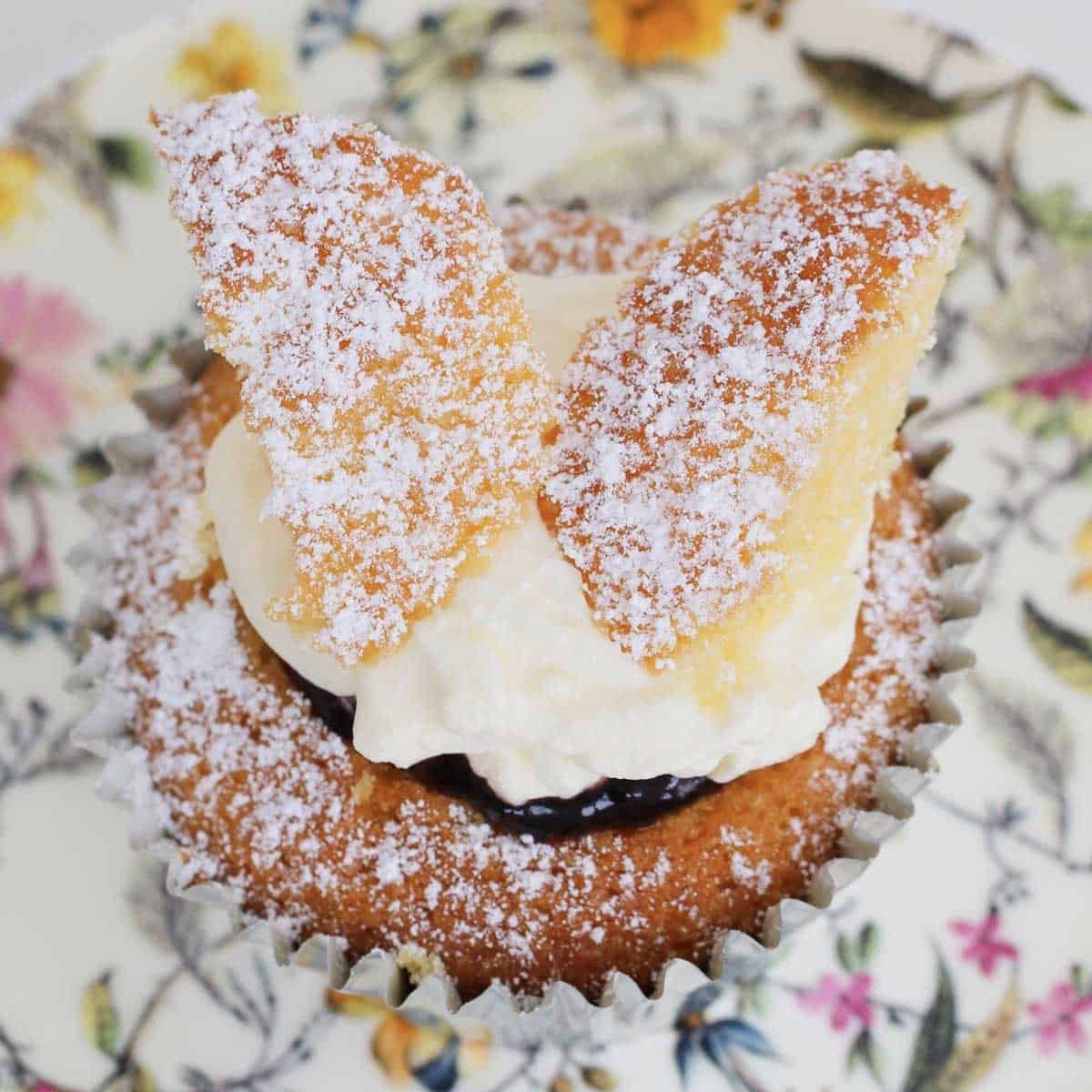 A butterfly cake dusted with icing sugar on a floral plate.