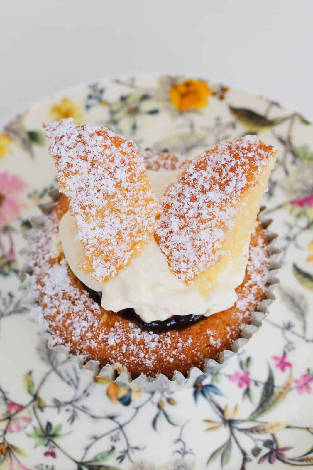Icing sugar sprinkled over a fairy cake served on a floral plate.