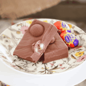 A floral plate with pieces of chocolate fudge filled with Cadbury creme eggs.