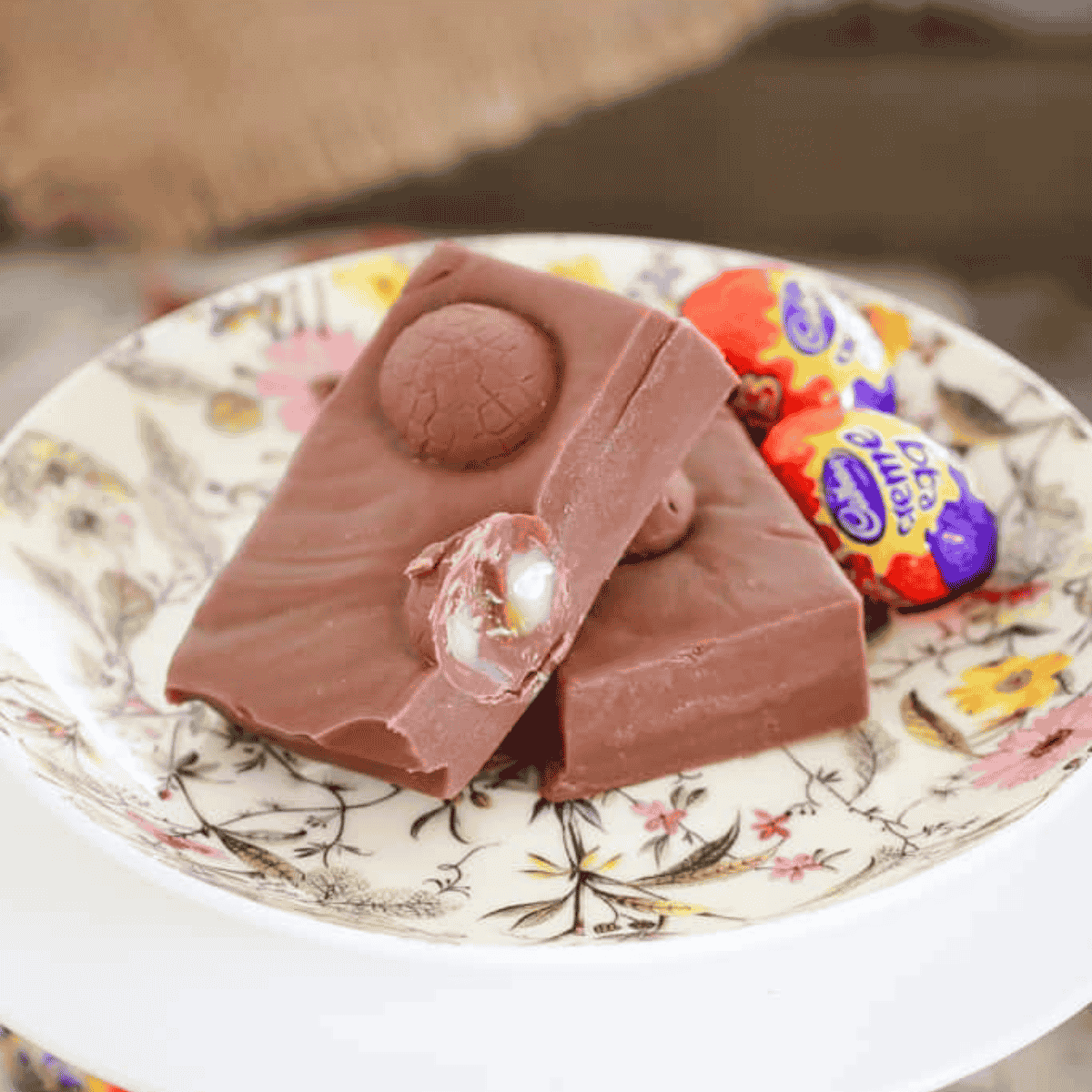 A floral plate with pieces of chocolate fudge filled with Cadbury creme eggs.