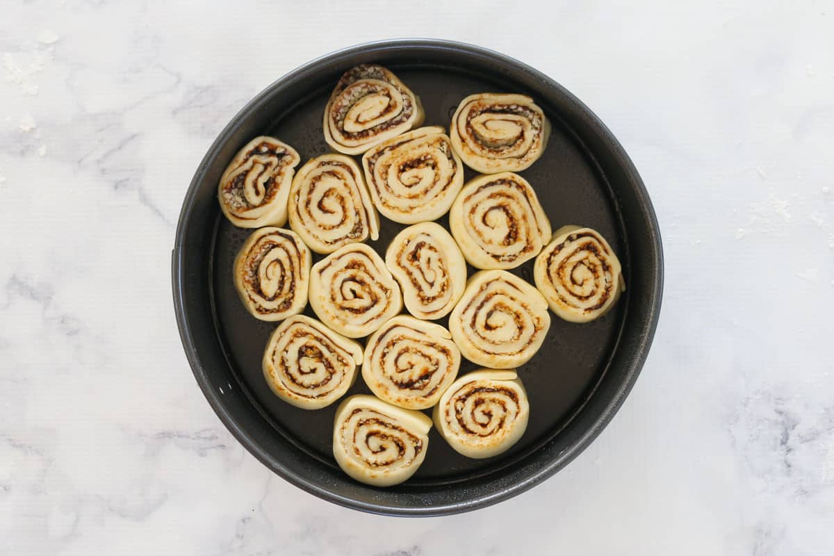 Dough scrolls with a cheese and Vegemite filling in a round baking tin.