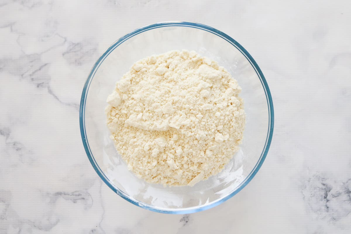 Self-raising flour and butter rubbed to resemble breadcrumbs, in a glass bowl.