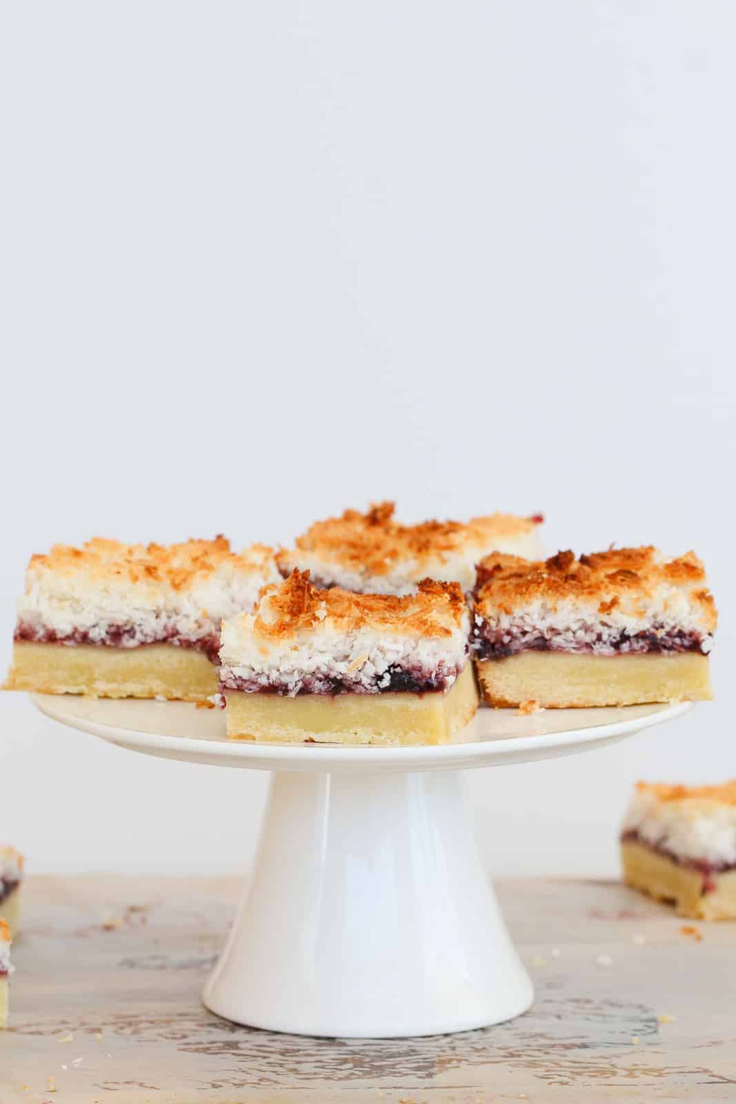 Pieces of Raspberry Coconut Slice on a white cake stand