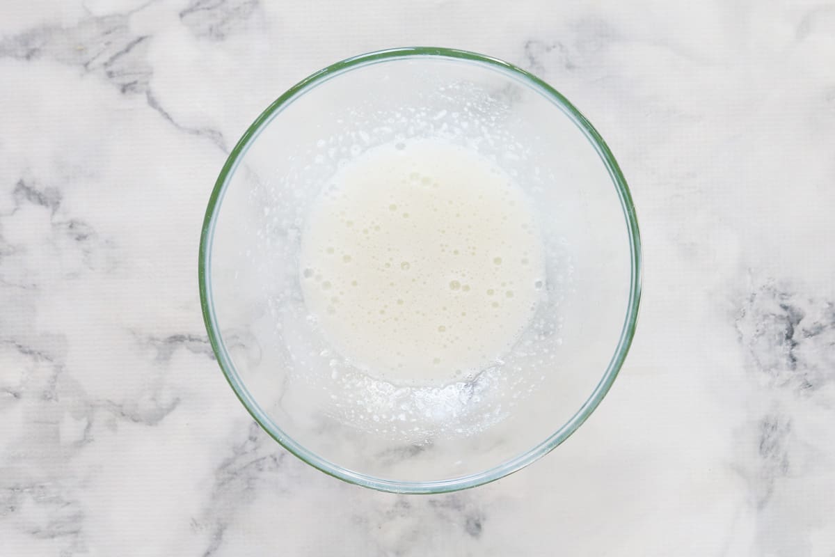 Egg whites and caster sugar whisked together in a glass bowl.