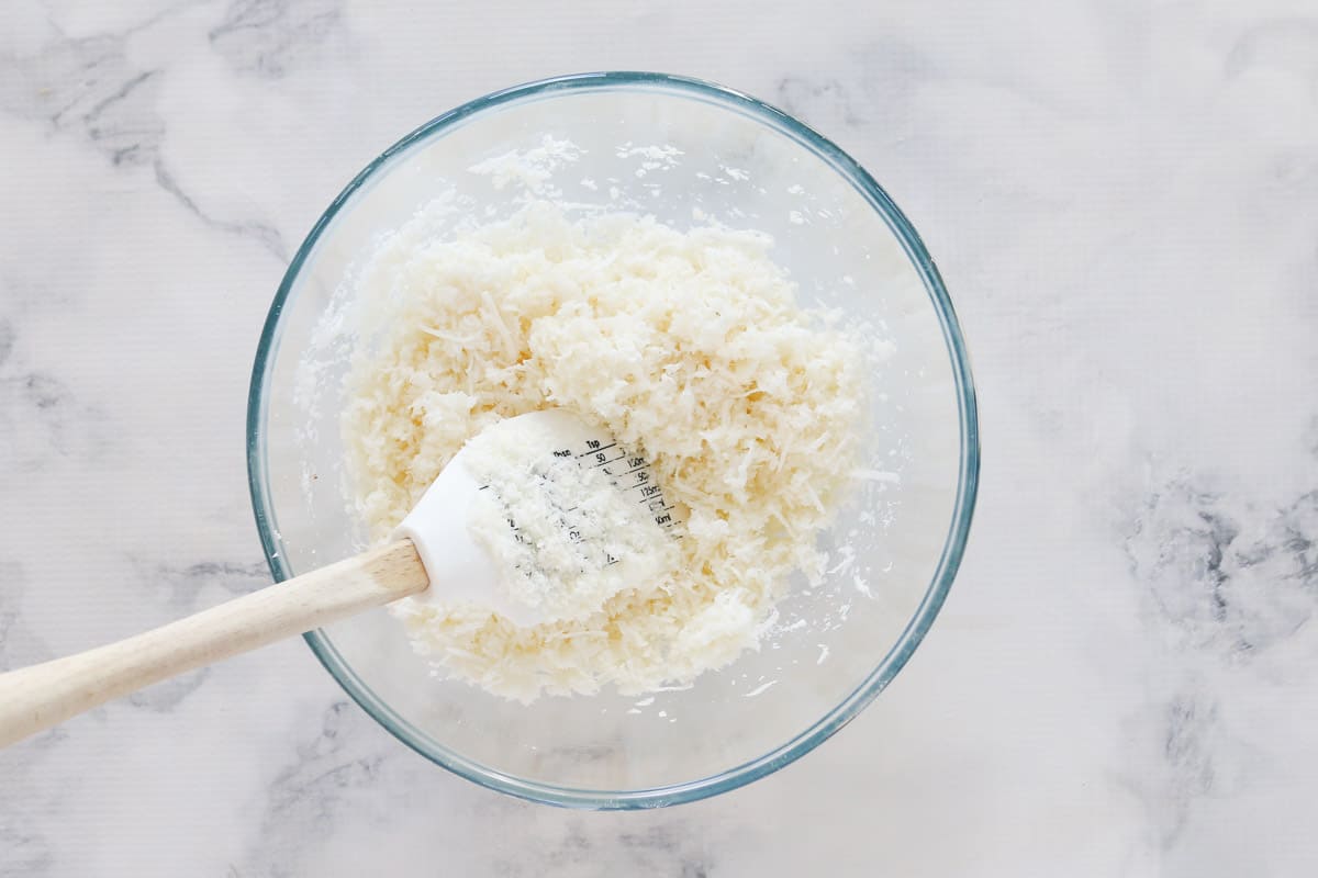 Coconut being mixed through egg white mixture  with a spoon.