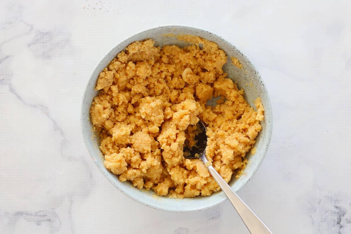 Biscuit crumbs mixed with melted butter in a bowl.