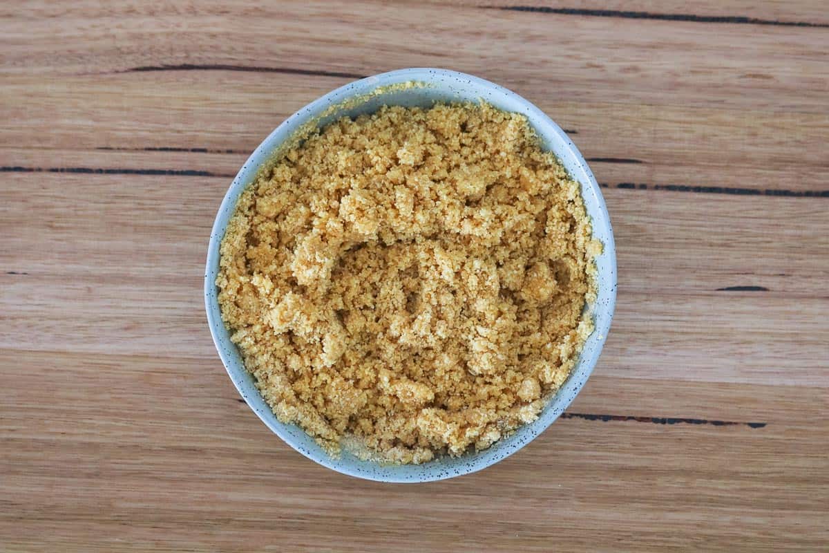 A bowl with cookie crumbs and melted butter mixed together. 