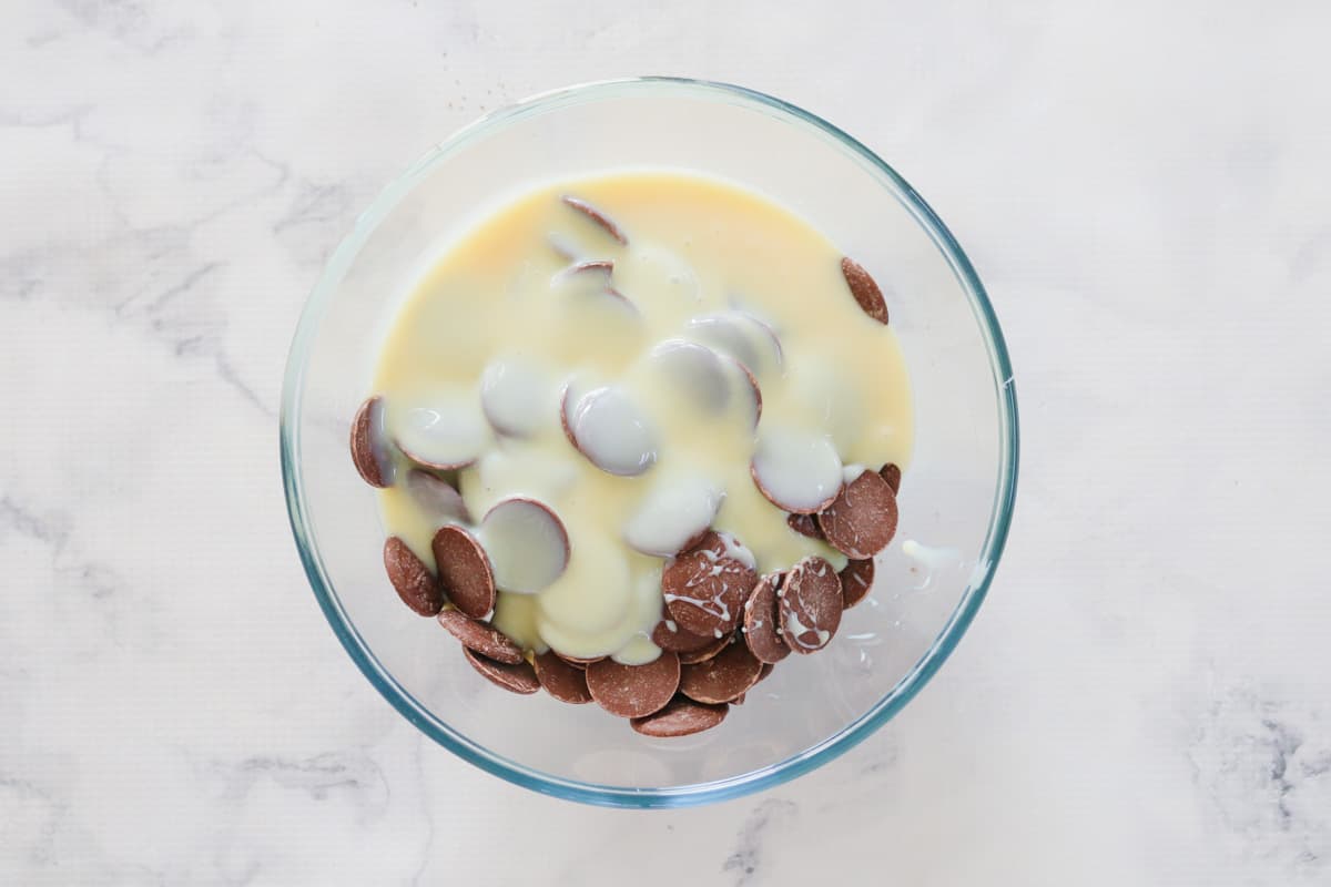Sweetened condensed milk and chocolate melts in a bowl.