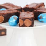 A white cake stand topped with moist brownies filled with Easter eggs,