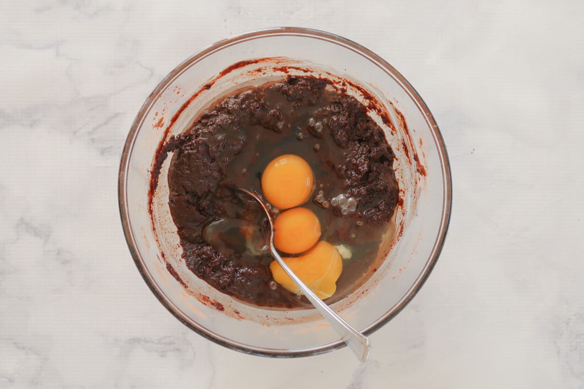 Eggs added to a bowl of chocolate mixture.