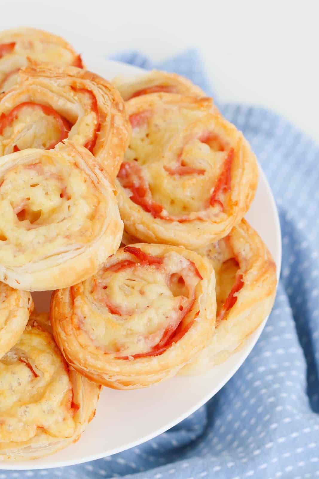 Ham and cheese roll ups in a pile on a plate.