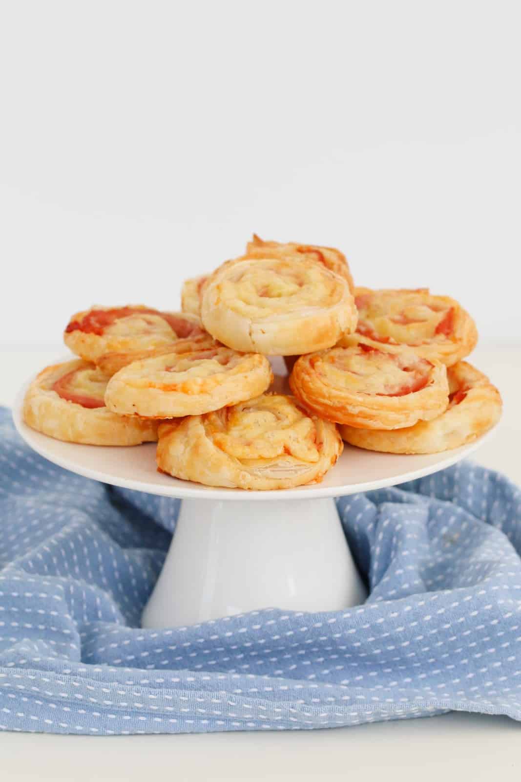 A white stand filled with savoury ham and cheese pinwheels.