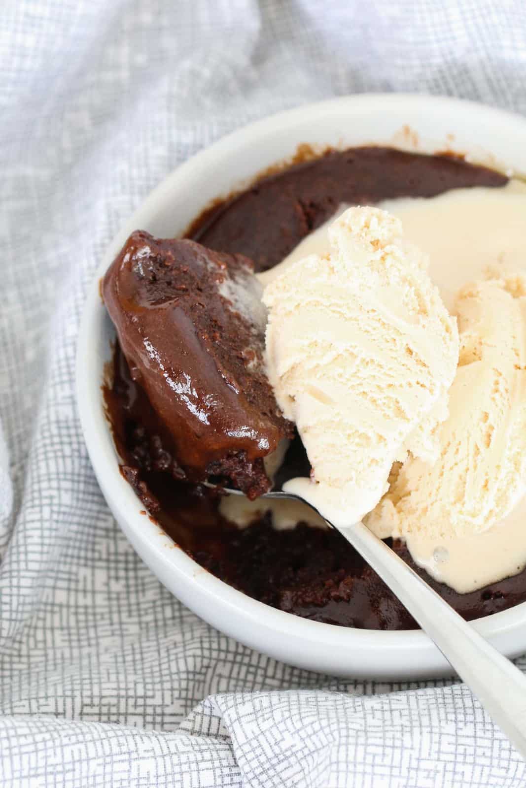 Close view of a microwave brownie in a white ramekin with a scoop of ice cream