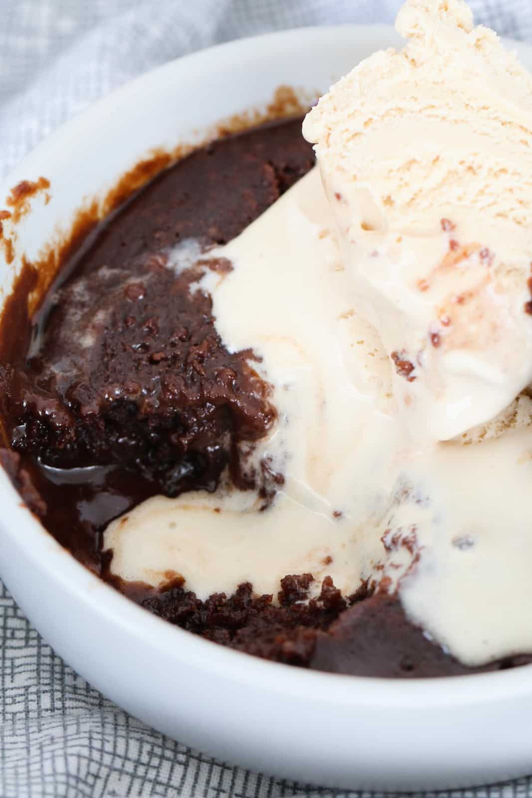 A close up view of chocolate brownie with ice cream in a small white bowl