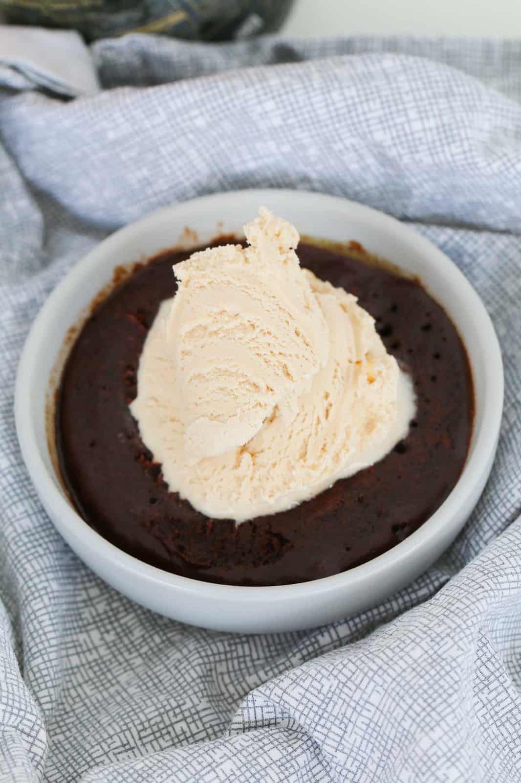 Top view of a microwave brownie in a white ramekin served with ice cream