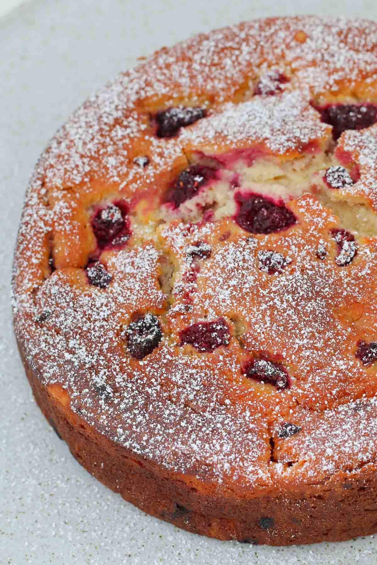 Overhead view of a raspberry ricotta cake dusted with icing sugar
