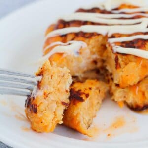 A fork with a mashed sweet potato and tuna cake on it.
