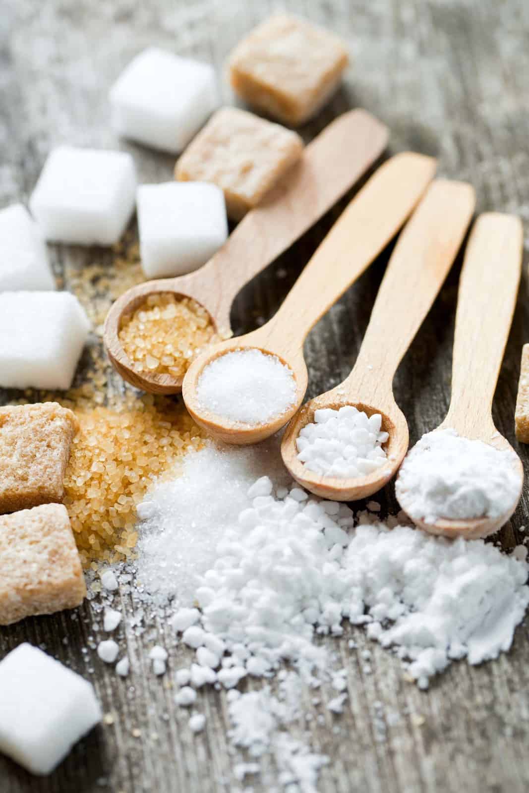 Spoons filled with different types of sugars.