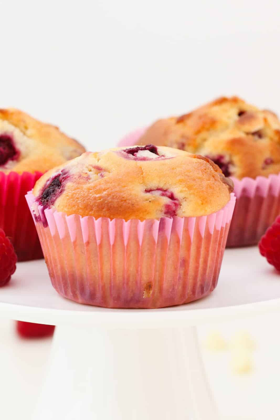 Muffins with raspberries and white chocolate chunks in pink muffin case liners.