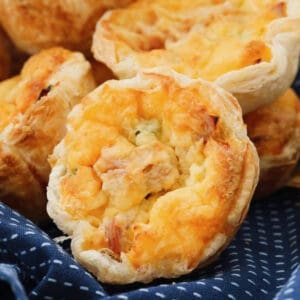 Close up image of a Corn, Ham and Cheese quiche in a puff pastry crust on a blue tea towel