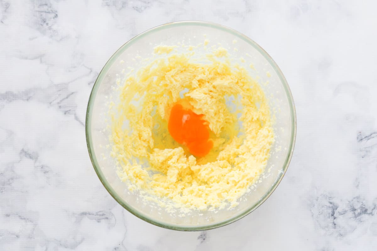 Egg on top of creamed butter and sugar in a bowl.