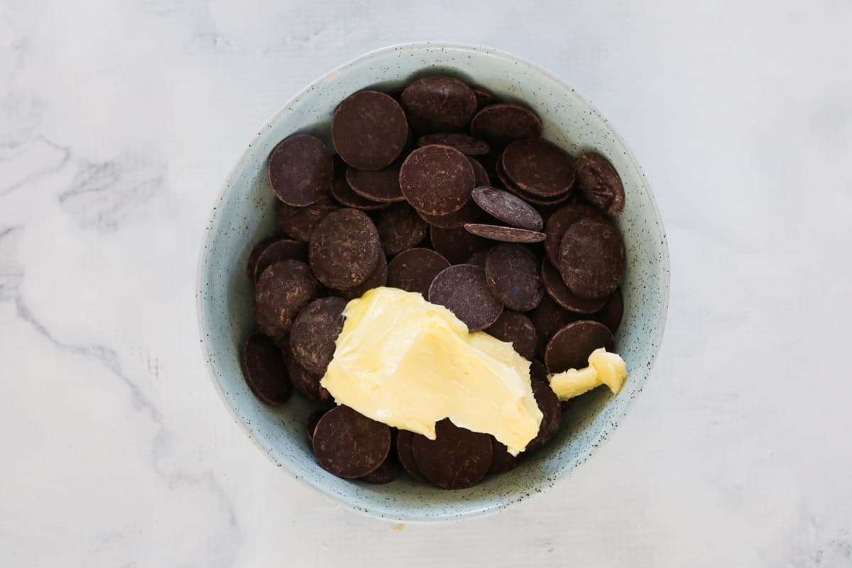 A white bowl with chocolate melts and butter