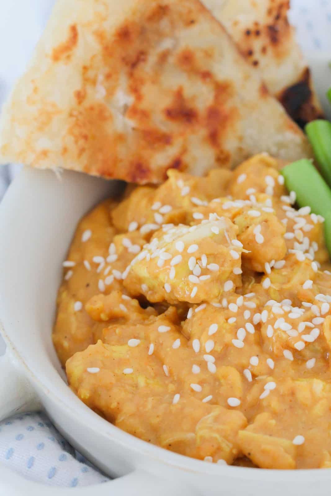 Butter chicken topped with sesame seeds in a bowl.