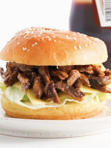 A pulled lamb burger with lettuce and cheese.