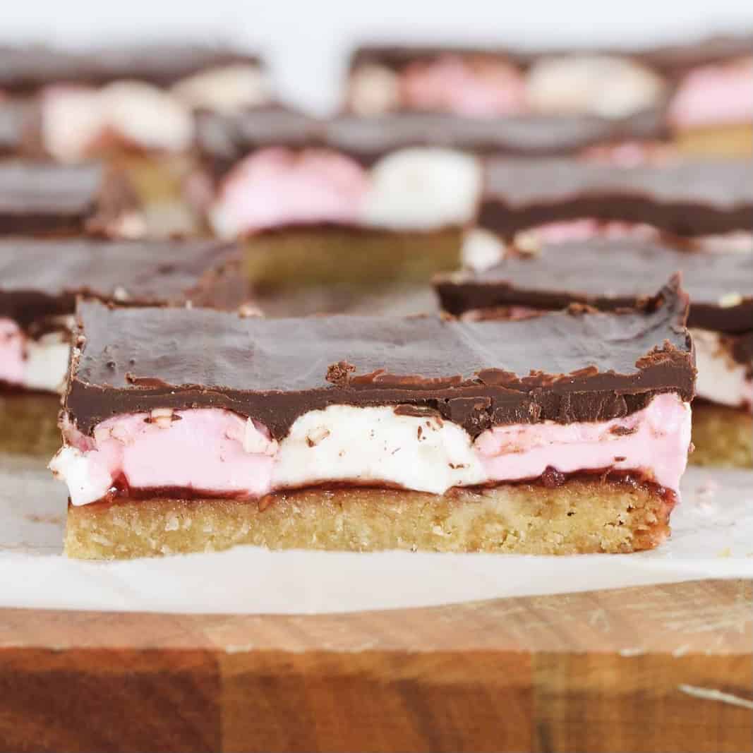 Pink and white marshmallows on a biscuit base with jam and chocolate.