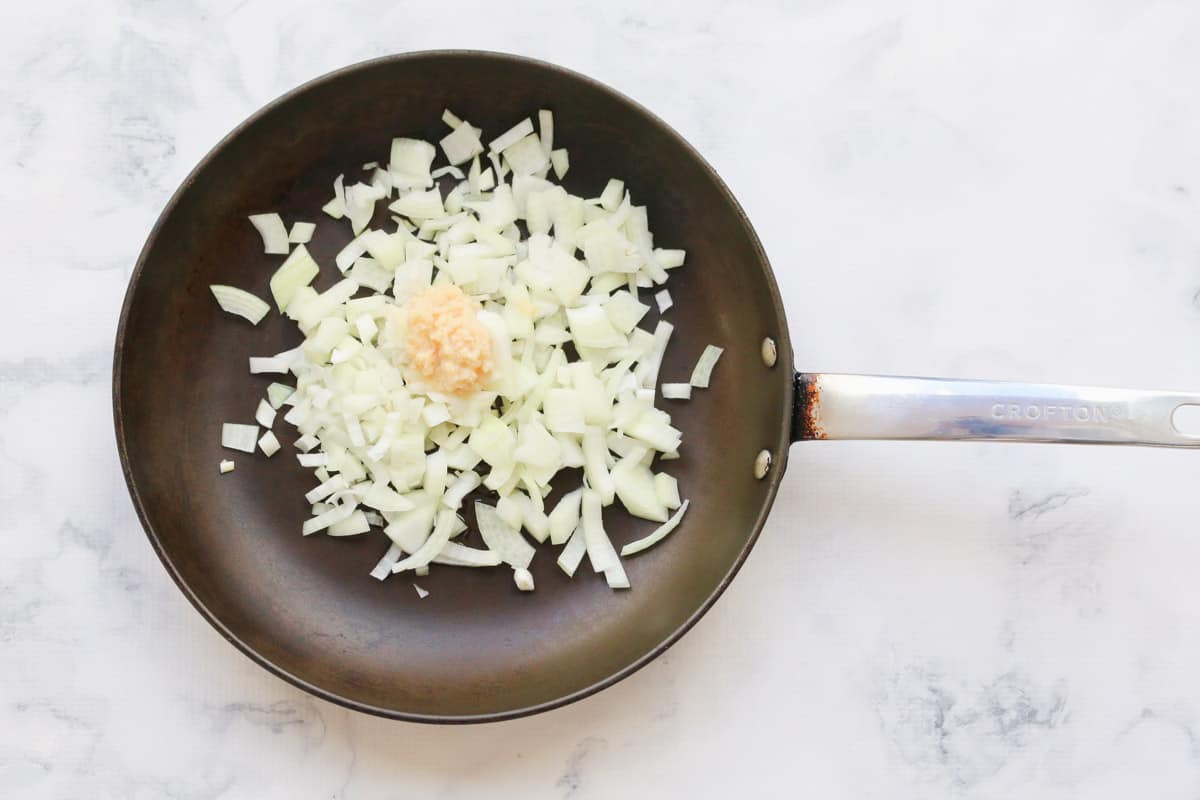a frying pan with diced onion and minced garlic